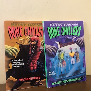 May include: Two paperback books with green, purple, and orange covers. The books are titled "Bone Chillers" and feature illustrations of a turkey monster and skeletons in a shop.