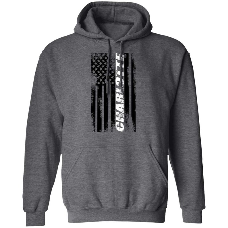 May include: A dark heather grey hooded sweatshirt with a distressed American flag design and the word "CHARLOTTE" in white lettering.