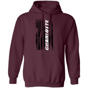 May include: Burgundy hooded sweatshirt with a distressed American flag design and the word "CHARLOTTE" in white text.