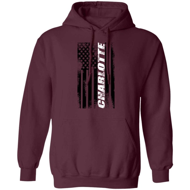 May include: Burgundy hooded sweatshirt with a distressed American flag design and the word "CHARLOTTE" in white text.