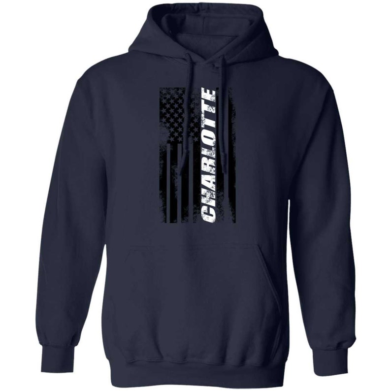 May include: Navy blue hooded sweatshirt with a distressed American flag design and the word "CHARLOTTE" in white lettering.