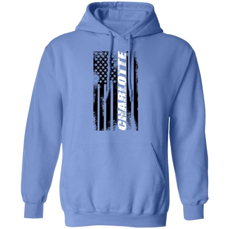May include: A light blue hooded sweatshirt with a distressed American flag design and the word "CHARLOTTE" in white lettering.