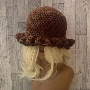 May include: A brown crocheted bucket hat with a ruffled brim.
