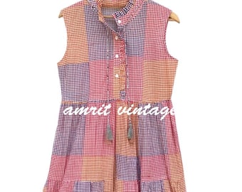 May include: Sleeveless patchwork dress in pink, orange, and purple gingham patterns. The dress features a mandarin collar, button-down front, and tassel details. The text "amrit vintage" is printed on the dress.