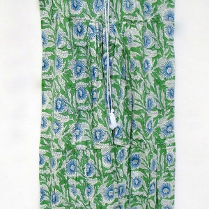 May include: A sleeveless green and white dress with a blue floral print. The dress has a ruffled neckline and a drawstring tie at the front.