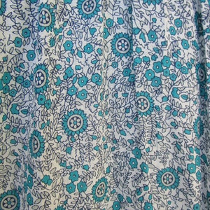 May include: White fabric with a blue and grey floral pattern. The pattern features small flowers and larger, more intricate flowers.