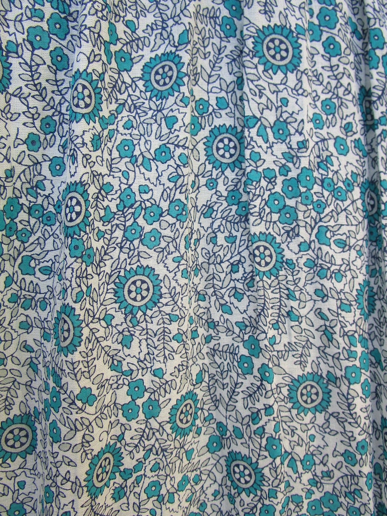 May include: White fabric with a blue and grey floral pattern. The pattern features small flowers and larger, more intricate flowers.