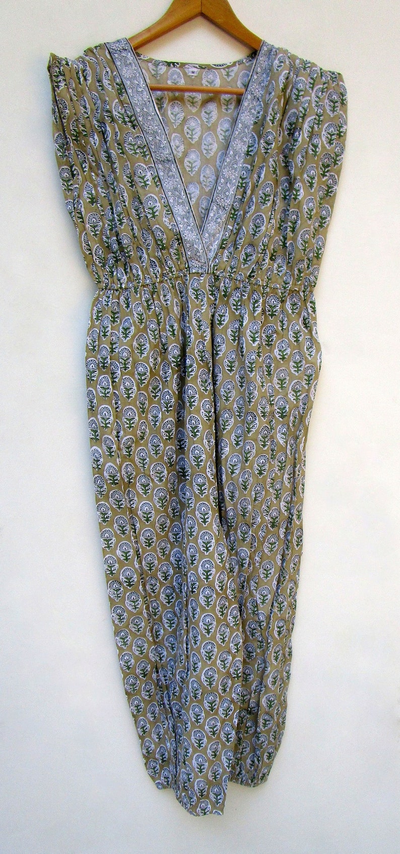 May include: A sleeveless, loose-fitting dress with a V-neckline and a floral print in shades of green, white, and brown.
