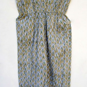 May include: A beige cotton dress with a floral print in shades of green and blue. The dress has a gathered waist and short sleeves.