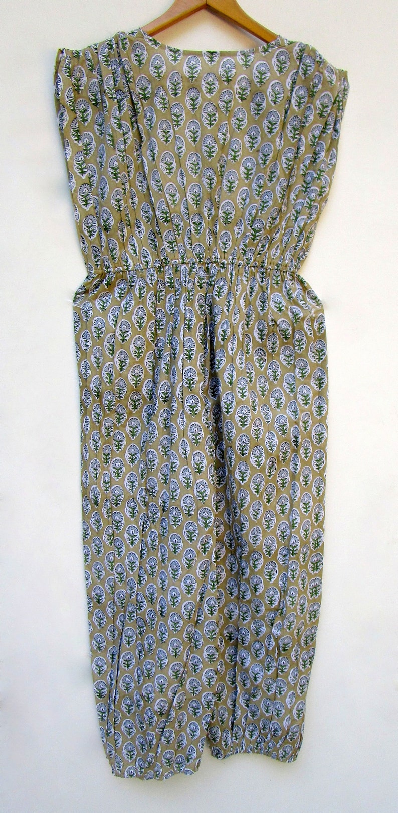 May include: A beige cotton dress with a floral print in shades of green and blue. The dress has a gathered waist and short sleeves.