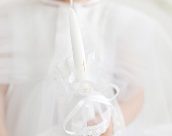 White wax candle with tulle decoration, Festive taper fire-stick with ribbon, Church celebration attribute with minimalistic golden cross