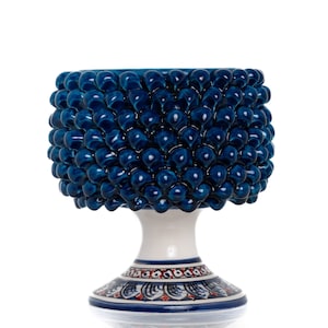 May include: A blue and white ceramic planter shaped like a pine cone. The planter has a textured surface and a base with a decorative pattern.