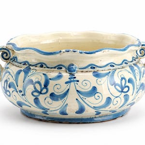 Könnte beinhalten: Eine große, cremefarbene Keramikschale mit gewelltem Rand und zwei Griffen. Die Schale ist mit blauen Blumenmustern und einem blauen Rand verziert. Die Schale hat einen Durchmesser von ca. 30 cm und eine Höhe von 15 cm.