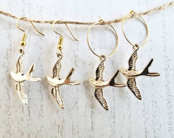 May include: Gold tone bird earrings. Two pairs of earrings, one pair is a hoop with a bird charm and the other pair is a dangle with a bird charm.