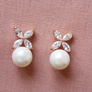 Puede incluir: Un par de pendientes de perlas con un delicado dise&ntilde;o floral con piedras de circonita c&uacute;bica transparentes. Los pendientes est&aacute;n engastados en un tono oro rosa.
