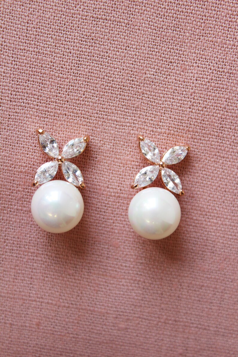 Puede incluir: Un par de pendientes de perlas con un delicado dise&ntilde;o floral con piedras de circonita c&uacute;bica transparentes. Los pendientes est&aacute;n engastados en un tono oro rosa.