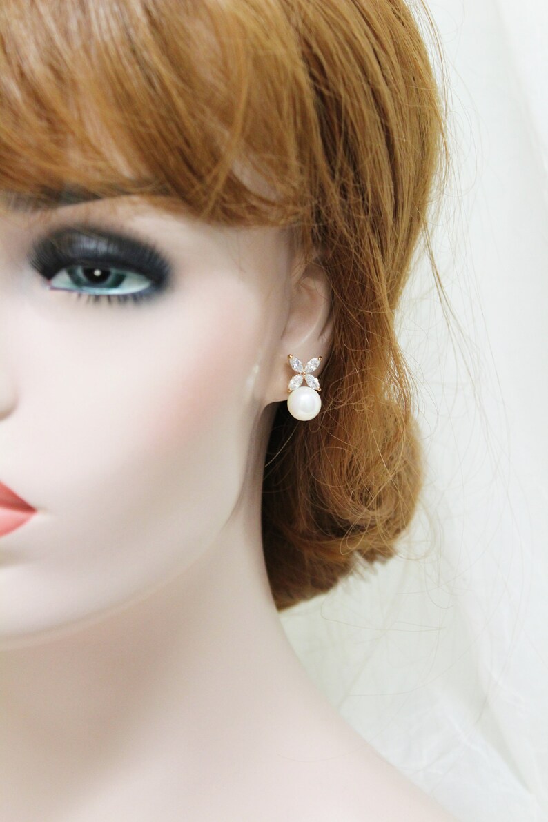 Puede incluir: Pendientes de oro con una perla y detalles de cristal transparente. Los pendientes tienen un dise&ntilde;o simple y elegante.
