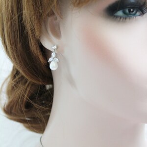 May include: Silver earrings with a pearl drop and clear crystal accents.