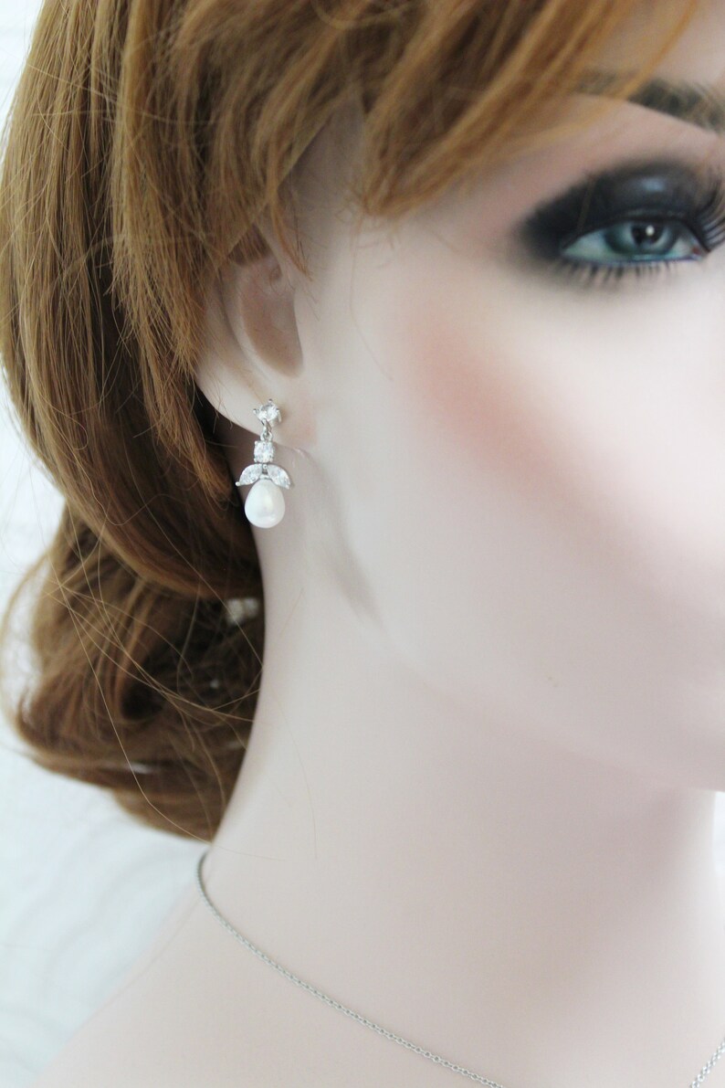 May include: Silver earrings with a pearl drop and clear crystal accents.