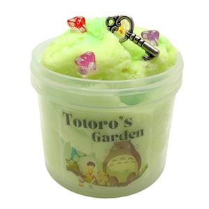 May include: A green slime with a key charm and colorful sprinkles in a clear plastic container with the text "Totoro's Garden" and a cartoon image of Totoro.