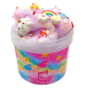 May include: A purple slime with glitter and colorful charms in a clear plastic container with a pink and blue rainbow design and the text "Sweet Dreams".