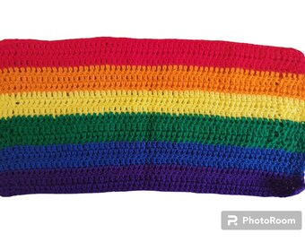 May include: A crocheted rainbow blanket with stripes of red, orange, yellow, green, blue, and purple.