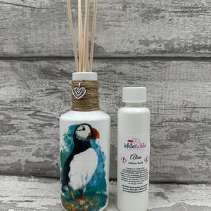 Peut inclure: Un diffuseur blanc avec un dessin de macareux, de la ficelle de jute et un charm en forme de cœur. Il comprend des bâtonnets en bois et une petite bouteille blanche étiquetée "Alien" par ickletickle.