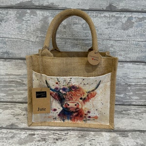 K&ouml;nnte beinhalten: Eine kleine braune Jute-Tragetasche mit einem Aquarellbild eines Highland-Rinds mit einer Blumenkrone. Die Tasche hat ein braunes Etikett mit der Aufschrift "Handmade with love". Die Tasche hat auch ein braunes Etikett mit der Aufschrift "Wisteria Mill Jute".