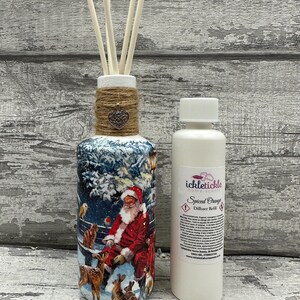 May include: A white bottle with a brown twine bow and a silver heart charm. The bottle is filled with a clear liquid and has a white label that says "ickletiickle Spiced Orange Diffuser Refill". The bottle is sitting on a wooden surface with a white background.