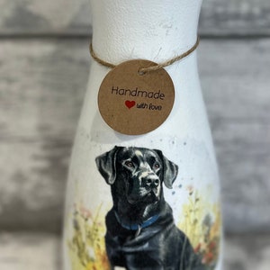 May include: White ceramic vase with a black Labrador Retriever illustration. The vase has a brown tag that says "Handmade with love".