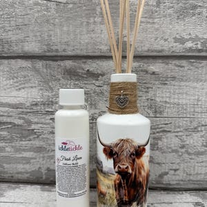 Peut inclure: Un diffuseur blanc avec une illustration de vache des Highlands, des bâtonnets en bois et un flacon de recharge. Le diffuseur est décoré avec de la ficelle et un charm en forme de cœur. Le flacon de recharge porte l'inscription "Fresh Linen".