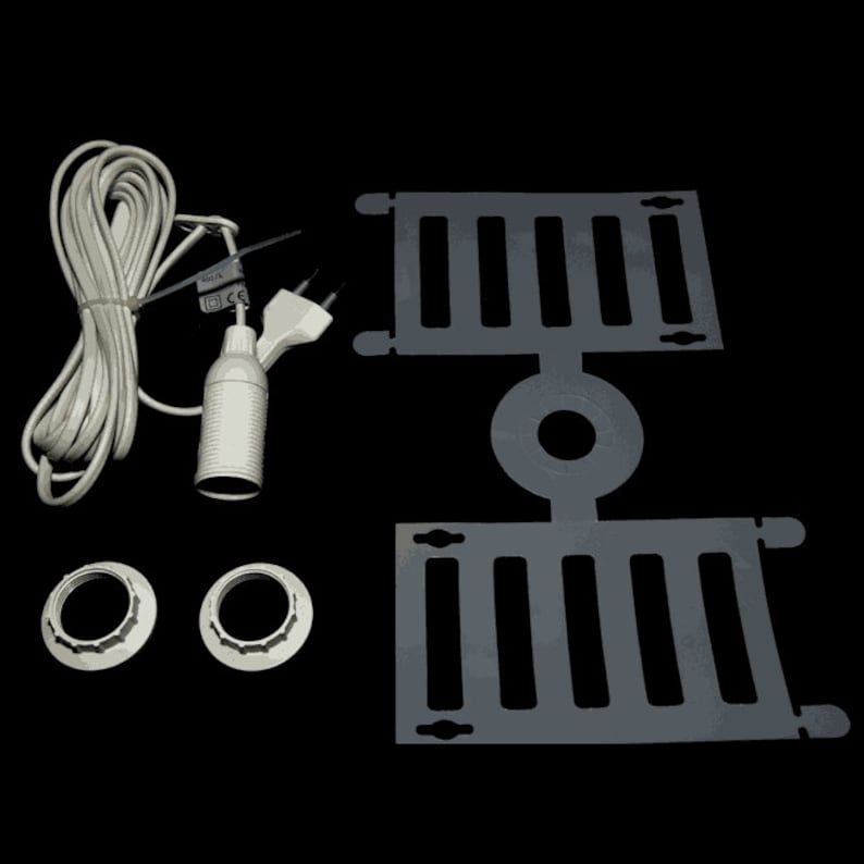 Puede incluir: Un conjunto de componentes el&eacute;ctricos blancos para una l&aacute;mpara, que incluye un cable con enchufe, un casquillo y dos placas de montaje para l&aacute;mpara de techo. Las placas son grises y tienen un patr&oacute;n de rejilla.