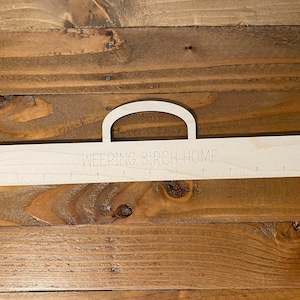May include: A wooden ruler with a handle, labeled "WEEPING BIRCH HOME" and marked with inches from 1 to 12.