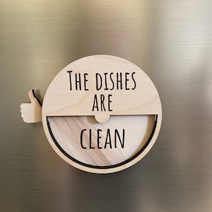 May include: A wooden round sign with a thumbs up icon and the text "The Dishes Are Clean".