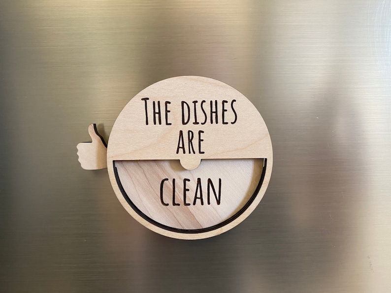 May include: A wooden round sign with a thumbs up icon and the text "The Dishes Are Clean".