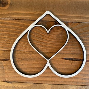 May include: A white wooden cutout of two overlapping hearts. The hearts are simple and elegant, with a smooth finish.