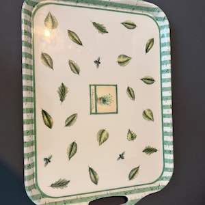 May include: A rectangular serving tray with integrated handles, featuring a white center decorated with scattered green leaves, small bees, and a central square graphic labeled Chamomile. The border has a green and white striped pattern.