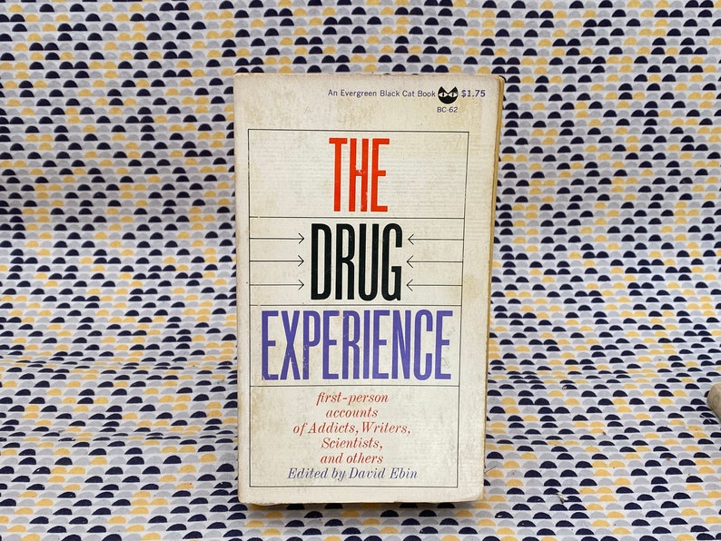May include: A white book with a black and red title "THE DRUG EXPERIENCE". The book is part of the Evergreen Black Cat Book series and costs $1.75. The book features first-person accounts of addicts, writers, scientists, and others. Edited by David Ebin.