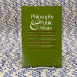 May include: A green book titled "Philosophy & Public Affairs" with the volume and number listed as "Volume 2, Number 4". The book cover features the text "Summer 1973" and lists the authors and titles of the articles included in the issue.