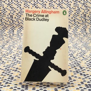 May include: Vintage paperback book titled "The Crime at Black Dudley" by Margery Allingham. The cover features a black silhouette of a sword against a cream background, with red and black text.