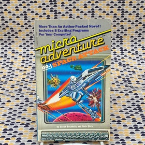 May include: A book cover for "micro adventure no. 1 SPACE ATTACK" by Eileen Buckboltz and Ruth Glick. The cover features a colourful illustration of a spaceship flying through space with a red planet in the background.