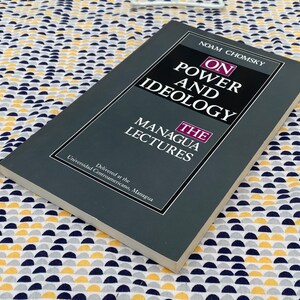 Op de afbeelding: Een grijs boek getiteld "On Power and Ideology: The Managua Lectures" van Noam Chomsky. Het boek werd gegeven aan de Universidad Centroamericano, Managua.