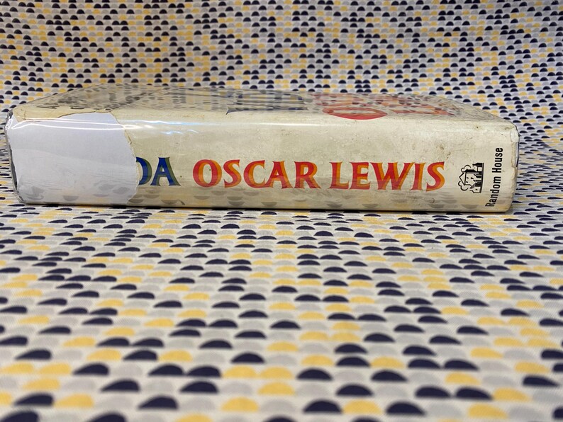 Op de afbeelding: Een wit boek met de titel "A DA Oscar Lewis" en de uitgever "Random House" gedrukt op de rug.