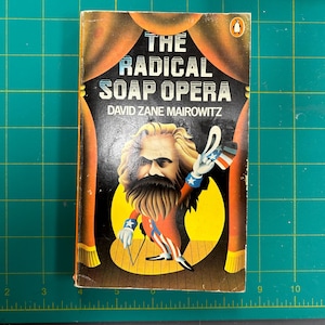 Może przedstawiać: Miękka okładka książki zatytułowanej "The Radical Soap Opera" autorstwa Davida Zane'a Mairowitza. Okładka przedstawia kreskówkową ilustrację mężczyzny z brodą i wąsem, który nosi czerwony i biały pasiasty garnitur i trzyma małą amerykańską flagę.