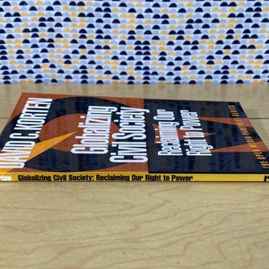 May include: A yellow, orange, and black book titled "Globalizing Civil Society: Reclaiming Our Right to Power" by David C. Korten. The book is part of the Open Media Pamphlet Series.