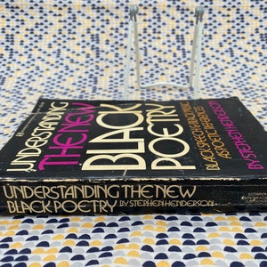 May include: A black and yellow paperback book titled "Understanding the New Black Poetry" by Stephen Henderson. The book cover features the title in bold, white letters with a pink background.