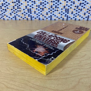 May include: A yellow paperback book titled "The Collapsing Universe: The Story of Black Holes" by Isaac Asimov. The cover features a black and white image of a galaxy with lightning bolts.