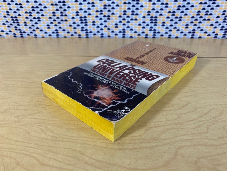 May include: A yellow paperback book titled "The Collapsing Universe: The Story of Black Holes" by Isaac Asimov. The cover features a black and white image of a galaxy with lightning bolts.