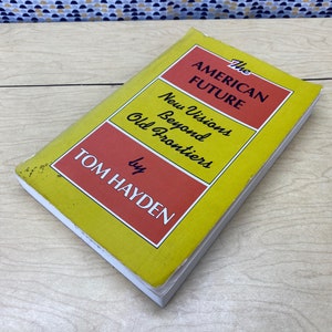 May include: A yellow and red book titled "The American Future: New Visions Beyond Old Frontiers" by Tom Hayden.