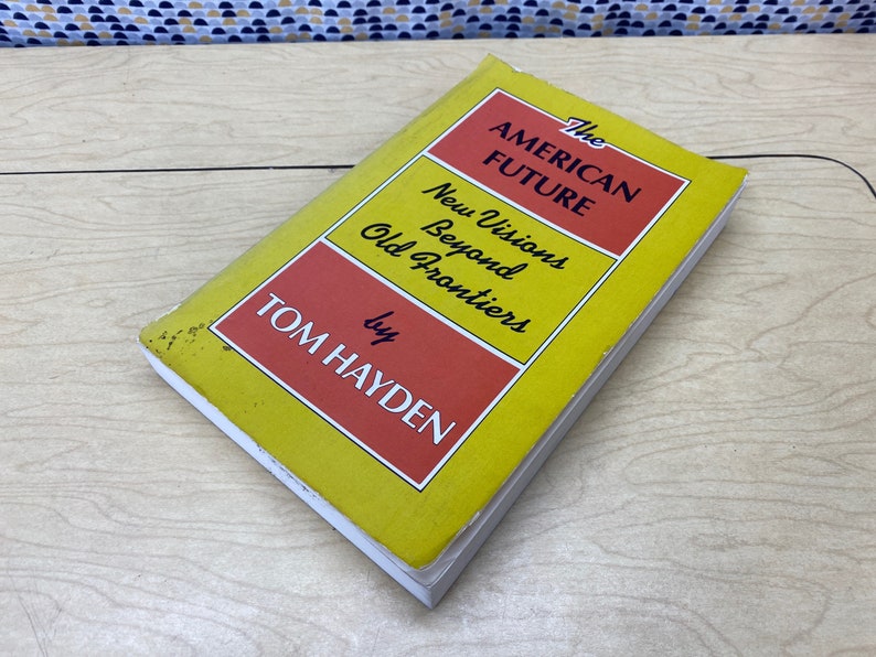 May include: A yellow and red book titled "The American Future: New Visions Beyond Old Frontiers" by Tom Hayden.